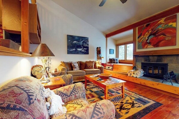 A cozy living room with a fireplace, a sofa, a coffee table, and a rug. - Lovely home with well-equipped kitchen & back deck - walk to shopping & dining (Wilson)