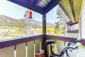 Eine überdachte Veranda mit einem feststehenden Ergometer, einem Holzstumpf und einem roten hängenden Gegenstand.