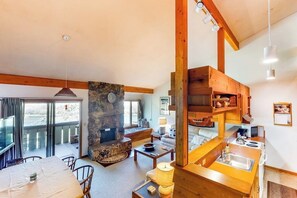 Ein gemütliches Wohnzimmer mit Kamin aus Stein, Holzbalken, Essbereich und einer Küche mit Holzböden.