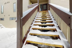 Eine Holztreppe mit Schneebedeckung, die zu einem Hauseingang führt.
