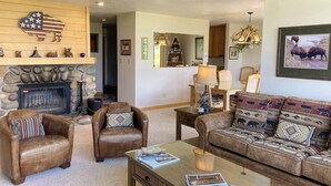A living room with leather armchairs, a sofa with patterned cushions, a glass coffee table, a fireplace, and a buffalo-themed wall decoration. - Beautiful family home w/full kitchen and gorgeous views from living room (Wilson)