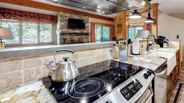 Una cocina con chimenea de piedra, estufa y un amplio ventanal.