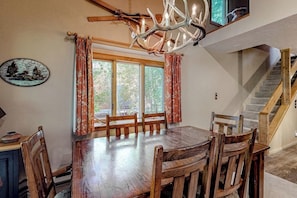 A dining area with a wooden table and chairs, a chandelier, and a staircase. - Beautiful condo with full kitchen, mountain views (Wilson)