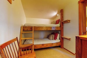 A bunk bed room with a wooden chair, a small shelf, and a door. - Beautiful country home with full kitchen & views from the private balcony (Wilson)