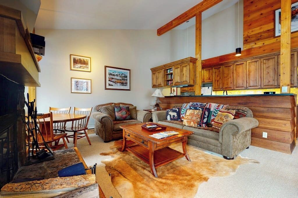 A cozy living room with a fireplace, wooden cabinets, a sofa, and a coffee table.