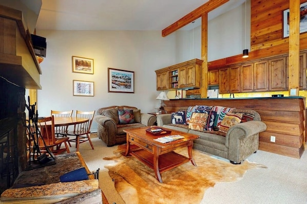A cozy living room with a fireplace, wooden cabinets, a sofa, and a coffee table. - Beautiful country home with full kitchen & views from the private balcony (Wilson)