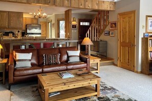 A spacious living area with a brown leather sofa, a wooden coffee table, and a television in the background. - Amazing country getaway with deck & mountain views (Jackson)