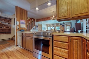 A kitchen with wooden cabinets, a stainless steel stove, and a chandelier. - Amazing country getaway with deck & mountain views (Jackson)