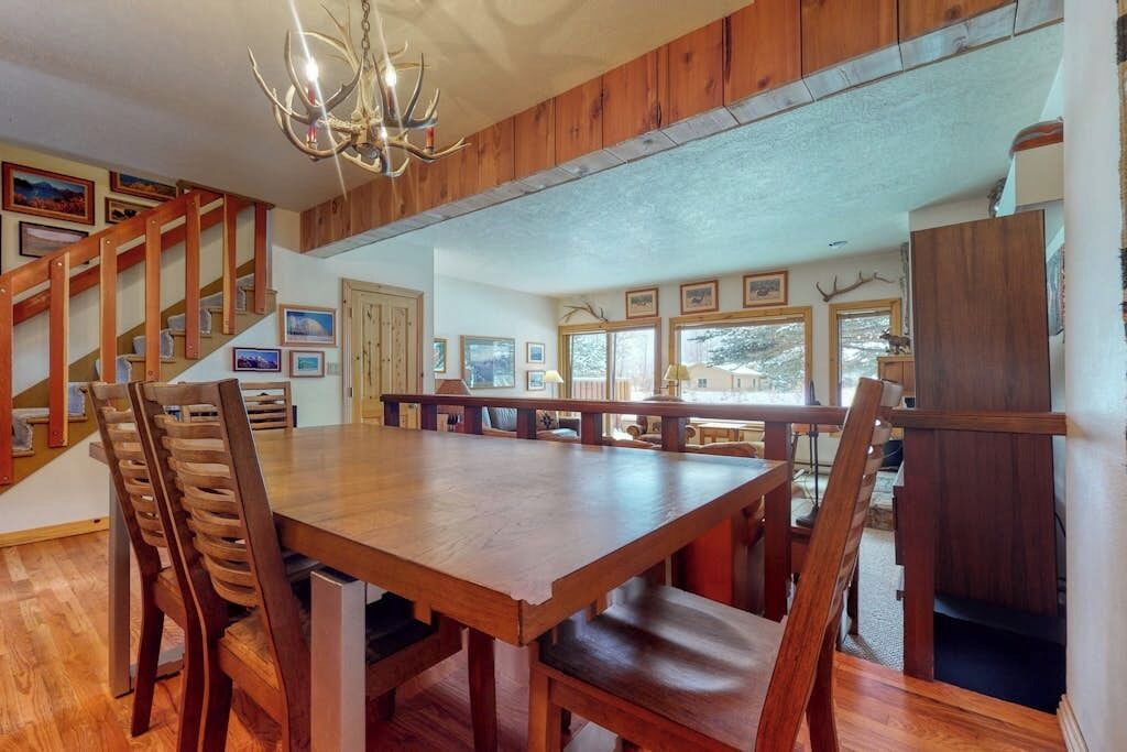 A dining area with a wooden table and chairs, a chandelier, and framed pictures on the walls.