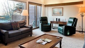 A living room with a sofa, two chairs, a coffee table, a lamp, and a painting on the wall. - Rustic townhome near golf course with private sauna & deck (Jackson)