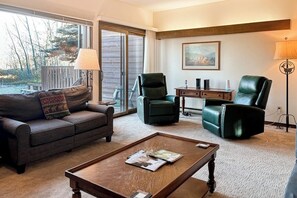 A living room with a sofa, two chairs, a coffee table, a lamp, and a painting on the wall. - Rustic townhome near golf course with private sauna & deck (Jackson)