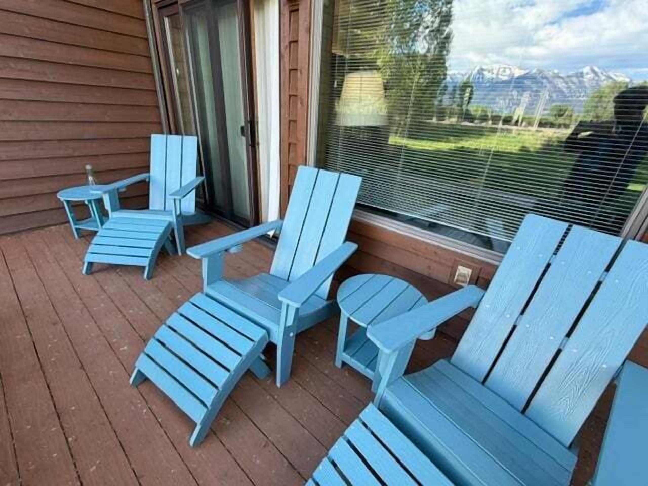 A wooden deck with four blue Adirondack chairs and a small table. - Rustic townhome near golf course with private sauna & deck (Jackson)