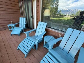 A wooden deck with four blue Adirondack chairs and a small table. - Rustic townhome near golf course with private sauna & deck (Jackson)
