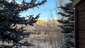A wooden cabin with a view of snow-covered mountains and a clear sky. - Rustic townhome near golf course with private sauna & deck (Jackson)