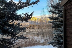 A wooden cabin with a view of snow-covered mountains and a clear sky. - Rustic townhome near golf course with private sauna & deck (Jackson)