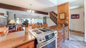 A modern kitchen with a large island, built-in appliances, and a wooden staircase. - Rustic townhome near golf course with private sauna & deck (Jackson)