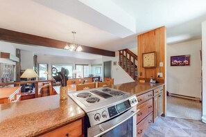 A modern kitchen with a large island, built-in appliances, and a wooden staircase. - Rustic townhome near golf course with private sauna & deck (Jackson)