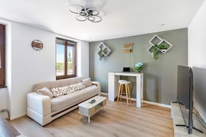 Ein modernes Wohnzimmer mit einer Couch, einem kleinen Tisch, einem Fernseher und dekorativen Wandelementen.