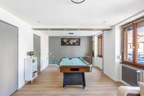 Una mesa de billar en un pasillo con vistas al exterior.