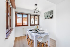 Un comedor con una mesa preparada para cuatro personas, un radiador y una ventana con persianas.