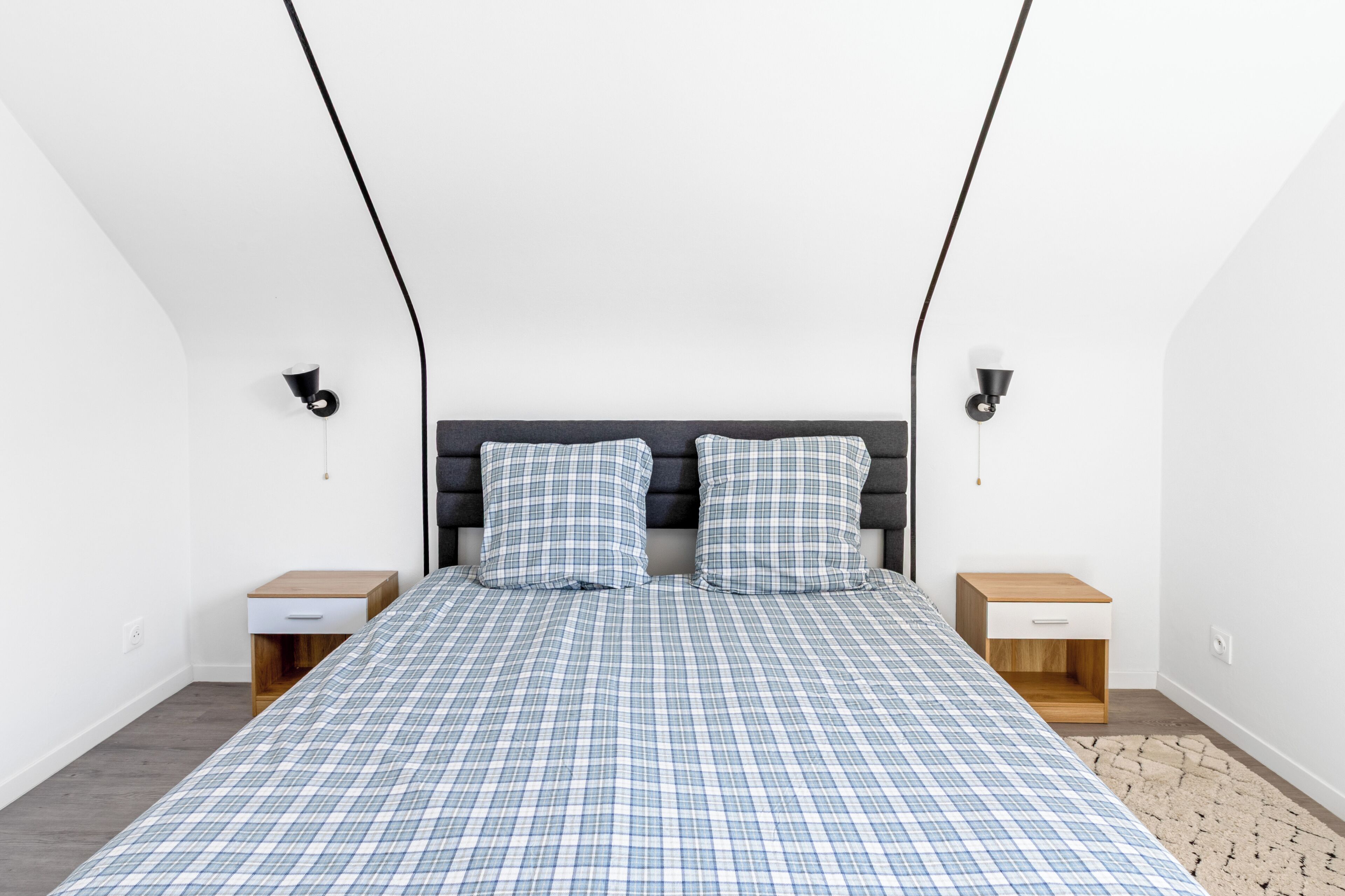 Une chambre à coucher comprenant un lit, deux tables de chevet et deux lampes fixées au mur.