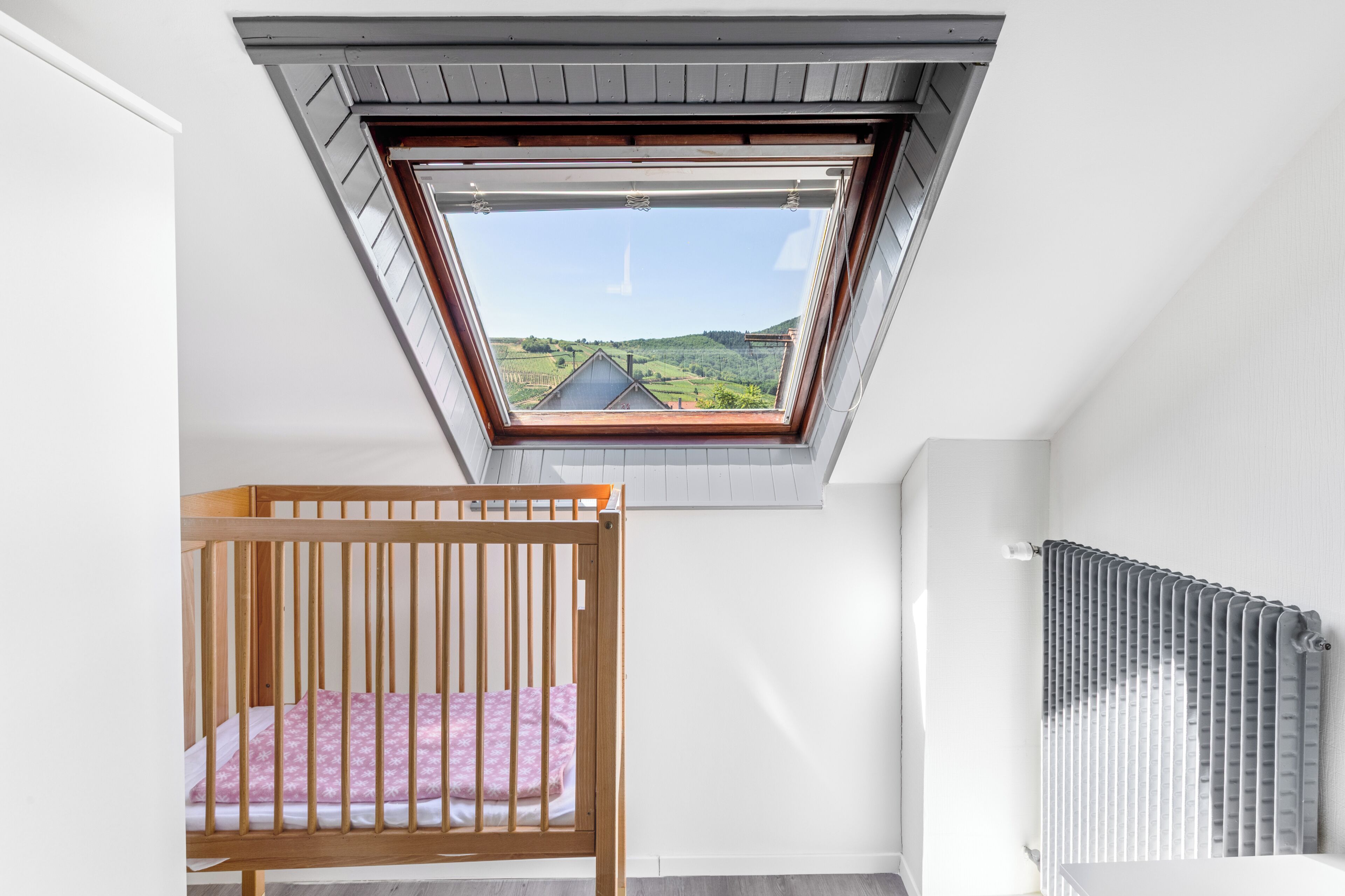 A room with a skylight, a wooden crib, and a radiator.