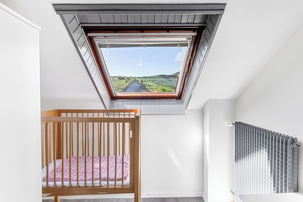 Una habitación con tragaluz, una cuna de madera y un radiador.
