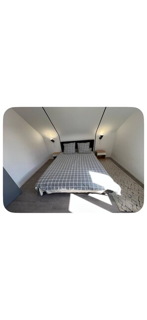 Ein Schlafzimmer mit einem Bett, zwei Nachttischen und Wandleuchten.