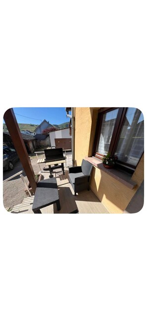 Ein Balkon mit Gartenmöbeln, Blick auf die Straße und ein Gebäude im Hintergrund.