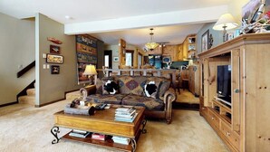 Ein Wohnzimmer mit einer Couch, einem Couchtisch und einem Holzkasten mit Fernseher.