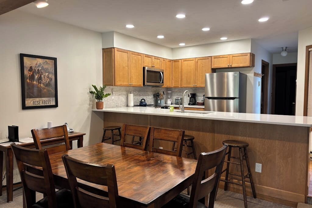 A modern kitchen with wooden cabinets, stainless steel appliances, and a central island with stools.