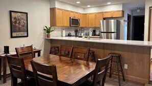 Een moderne keuken met houten kastjes, roestvrijstalen apparatuur en een centraal kookeiland met krukken.