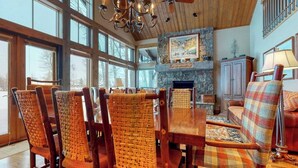 Un comedor con sillas de madera, chimenea y candelabro.