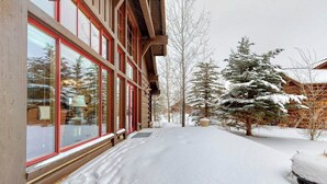 Un sendero cubierto de nieve que lleva a un edificio con amplios ventanales y fachada de madera.