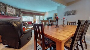 A dining area with a wooden table and chairs, a fireplace, a television, and a chandelier. - Welcoming, well-equipped condo with furnished deck, jetted tub & fireplace (Jackson)