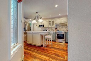 A kitchen with white cabinetry, a central island, pendant lighting, and a stainless steel oven. - Welcoming, well-equipped condo with furnished deck, jetted tub & fireplace (Jackson)