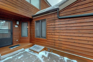 A wooden cabin with a front door, two windows with shutters, a small porch, and a metal gutter. - Welcoming, well-equipped condo with furnished deck, jetted tub & fireplace (Jackson)