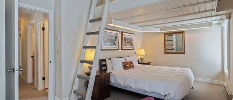 A bedroom with a loft bed, a ladder, a nightstand, a chair, and a window.