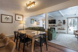 A spacious living area with a wooden dining table, green sofa, and a fireplace. - Inviting condo with mountain views, great location & fireplace (Jackson)