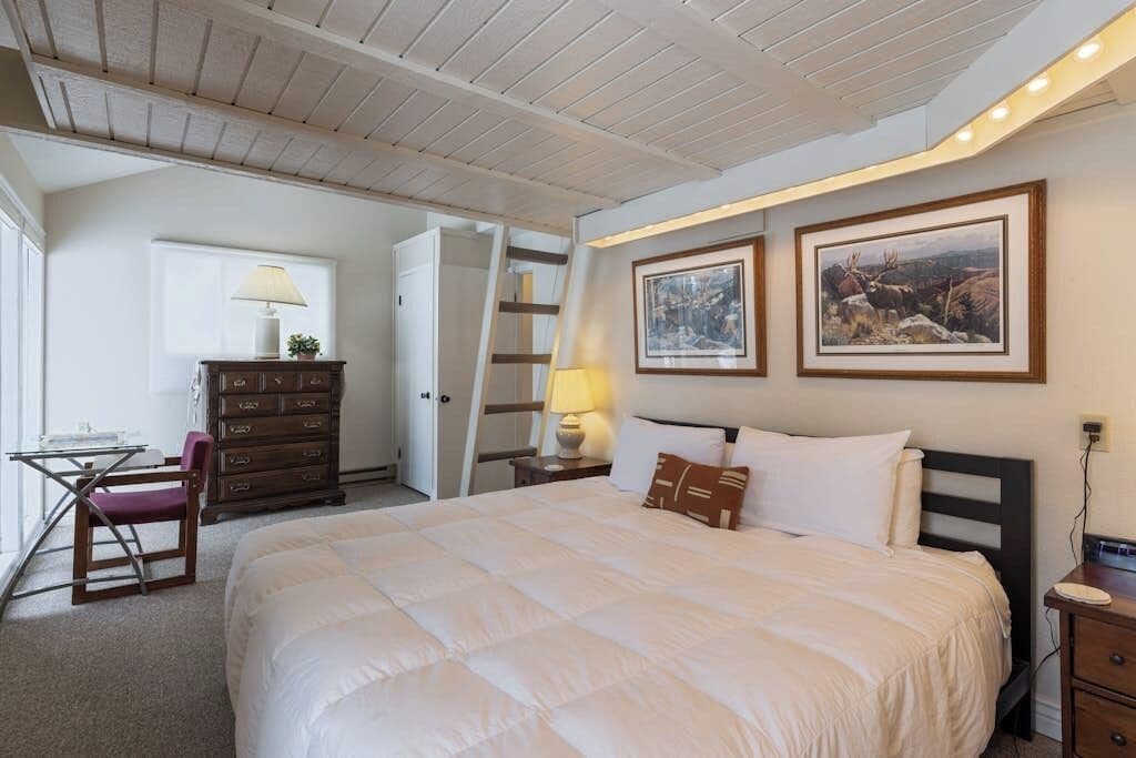 Ein Schlafzimmer mit einem großen Bett, einem Schreibtisch mit Stuhl, einer Kommode und zwei gerahmten Bildern an der Wand.