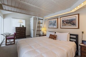 A bedroom with a large bed, a desk with a chair, a dresser, and two framed pictures on the wall. - Inviting condo with mountain views, great location & fireplace (Jackson)