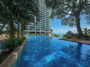 A hotel with a large pool, palm trees, and a view of the ocean. - Stunning Beachfront Condo in P.H. Bahia (Nueva Gorgona)