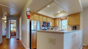 A kitchen with wooden cabinets, a stainless steel refrigerator, and a microwave.