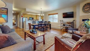 A spacious living room with a sofa, coffee table, and a dining area with chairs and a table.
