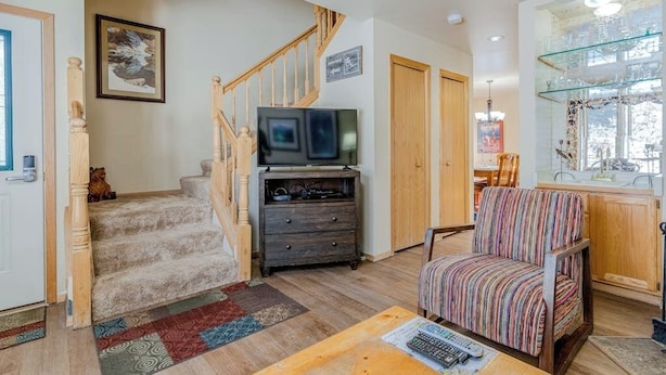 Un salon avec un escalier, un téléviseur, un fauteuil à rayures et une vitrine.