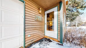 Une maison en bois avec une porte de garage, une pancarte de bienvenue et une porte donnant sur l’intérieur.