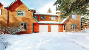Une maison en bois avec un garage, entourée de neige.