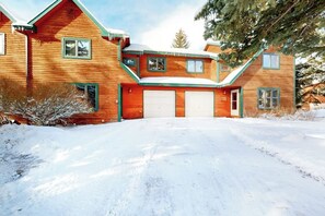 A wooden house with a garage, surrounded by snow. - Roomy 2-story home with furnished deck, grill, fireplace, & great location (Jackson)