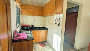 A kitchen with wooden cabinets, a microwave, a gas stove, and a sink. - Zebra Nest Apartpment (Kilimanjaro Region)