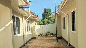 A narrow corridor with tiled flooring, potted plants, and a bucket on the ground. - Zebra Nest Apartpment (Kilimanjaro Region)